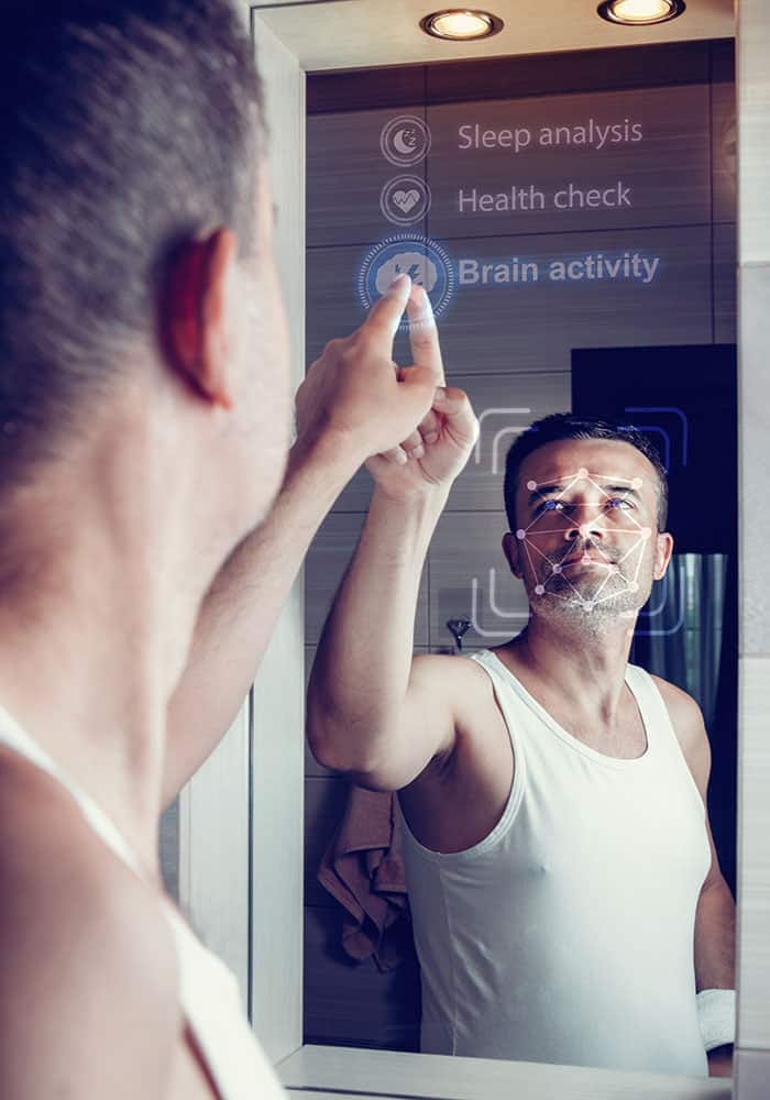 A man looks into a smart mirror and selects health parameters after waking up in the morning.